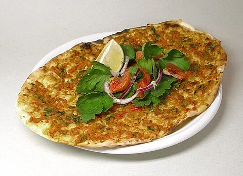 lahmacun: a dish of Arab origin consisting of a round, thin piece of dough topped with minced meat (most...
