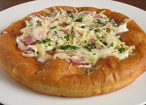 langos: a traditional Hungarian fried dough, usually seasoned with garlic, sour cream or cheese and sold as...