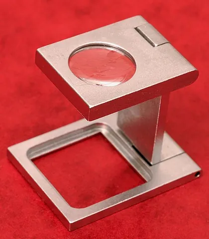 linen tester: a folding magnifying glass which, when unfolded, forms a frame for the lens at a pre-focussed...