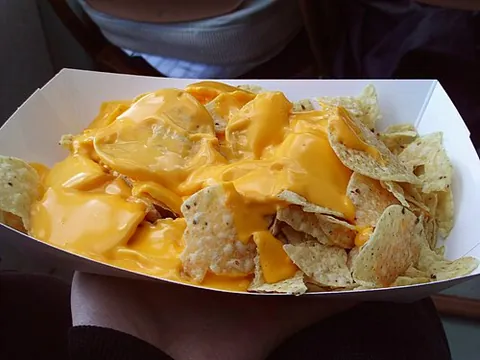 nacho cheese: a processed cheese sauce mixed with peppers and spices, most often eaten with nachos