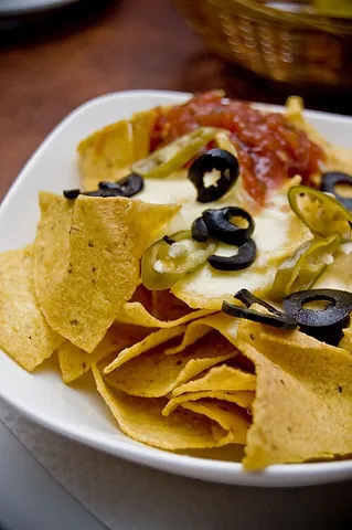 nachos: a Mexican dish of tortilla chips, covered in melted cheese and sometimes other ingredients