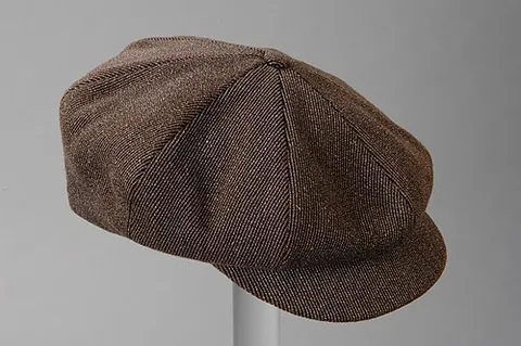 newsboy cap: a round hat, similar in style to a flat cap, usually made from eight pieces of cloth and paneled...