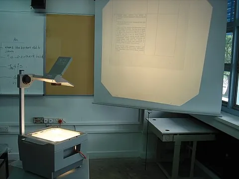 overhead projector: a projector that projects an image over the heads of the viewers onto a screen in front of them