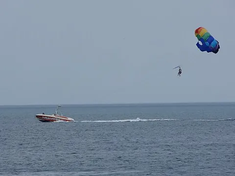 parasail: a wing-shaped parachute that lifts a rider in a harness when towed by a motorboat etc