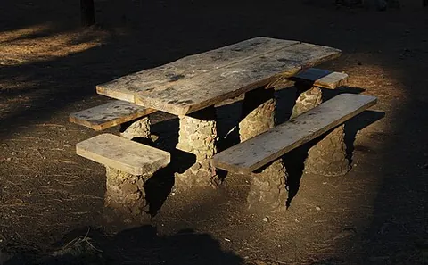 picnic table: an outdoor table with benches attached, intended for picnicking, or sometimes used as a skatepark...