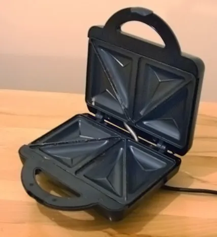 pie iron: a cast iron cooking appliance with a clamshell design used for making toasties