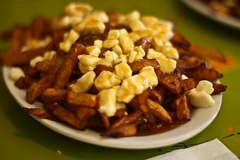 poutine: a dish consisting of French fries topped with cheese curds and gravy, eaten primarily in Canada
