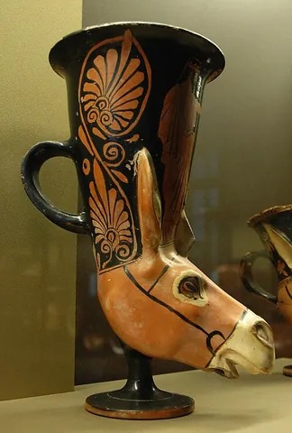 rhyton: a container from which fluids are intended to be drunk, having one handle and usually a base in the...