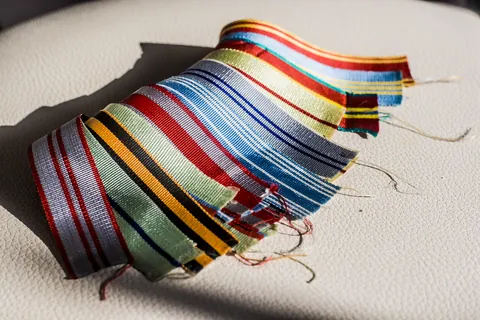 ribbon: a long, narrow strip of material used for decoration of clothing or the hair or gift wrapping