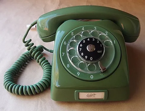 rotary dial: a disk with finger holes, used to enter numbers by rotating the disk forward and letting it slide...