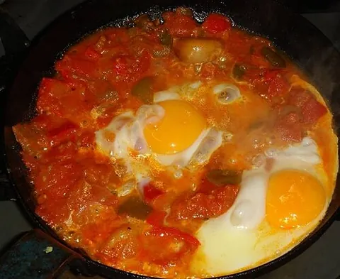 shakshuka: a Maghrebi dish of eggs simmered in a mixture of chopped tomatoes, chilies, cumin, peppers, and...