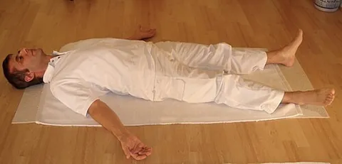shavasana: a resting pose in which one lies flat on one's back with the arms and legs slightly spread and eyes...