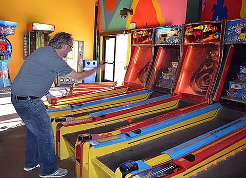 skee ball: an early arcade redemption game in which balls are rolled up an inclined lane, aimed at holes of...