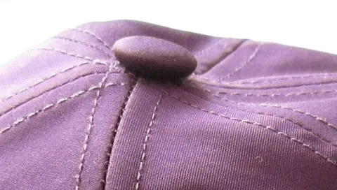 squatchee: a small, cloth-covered button affixed to the top of a baseball cap that holds together the panels...