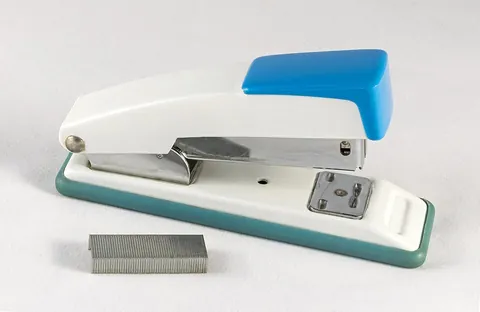 stapler: a device which binds together sheets of paper by driving a thin metal staple through the sheets and...