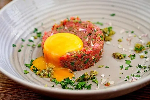 steak tartare: a French dish made of raw minced beef steak, often served with onions, capers and other ingredients