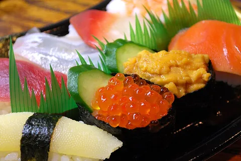 sushi: a Japanese dish made of small portions of sticky white rice flavored with vinegar, usually wrapped...