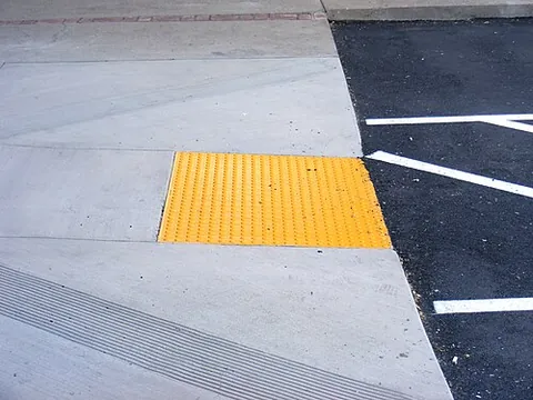 tactile paving: a system of textured ground surface indicators found on stairs, railway station platforms etc., to...