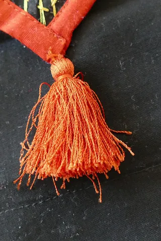 tassel: a ball-shaped bunch of plaited or otherwise entangled threads from which at one end protrudes a...