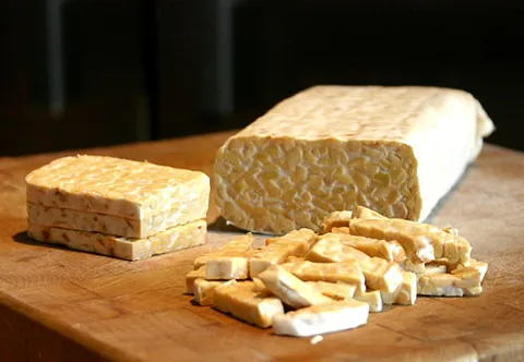tempeh: an Indonesian food made from partially-cooked soybeans fermented by a fungus (either Rhizopus...