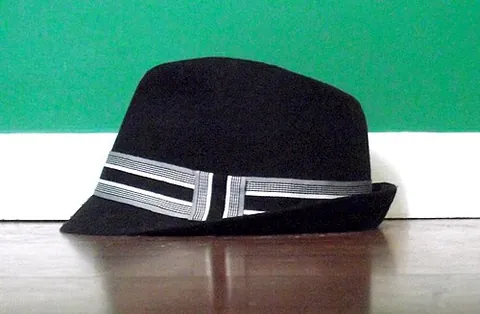 trilby: narrow-brimmed type of felt hat, described as having a "shorter brim which is angled down at the...