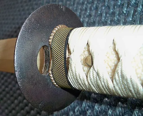 tsuba: the guard at the end of the grip of a Japanese sword or bladed weapon