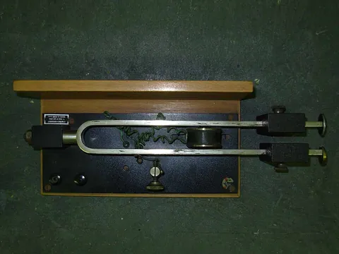 tuning fork: a fork-shaped object which emits a tone of a specific frequency when struck, producing a reference...