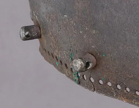vervelle: a rivet containing a hole, or a staple, on a medieval helmet, by which a camail was attached (or...