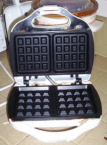 waffle iron: a cooking appliance, with hinged, indented metal plates, used to make waffles