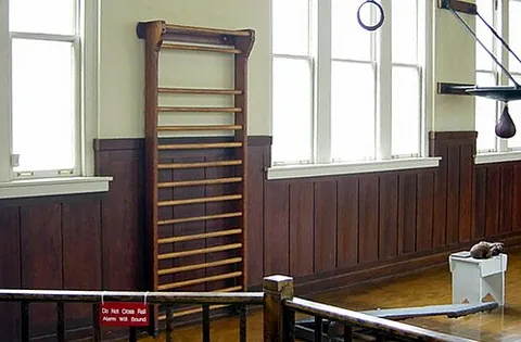 wall bars: a type of exercise equipment consisting of a ladder-like series of horizontal bars, used for...
