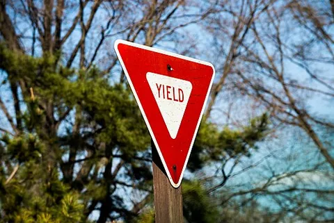 yield sign: a road sign which instructs road users to give right of way to other traffic
